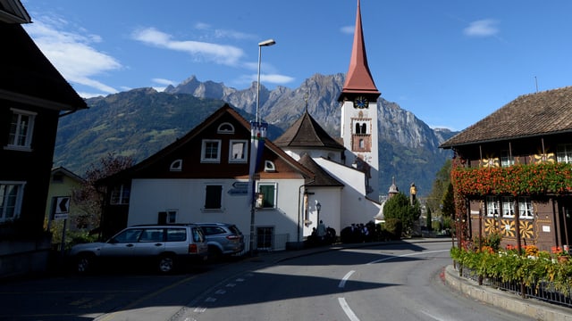 Dorfteil mit Strasse, Häuser und Kirche - im Hintergrund hohe Berge. Dorfteil mit Strasse, Häuser und Kirche - im Hintergrund hohe Berge.