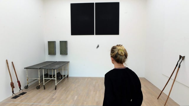 Eine Besucherin vor Beuys' Installation «Zeige deine Wunde», das sich aus Rollbahren, landwirtschaftlichen Geräten und schwarzen Flächen zusammensetzt. Eine Besucherin vor Beuys' Installation «Zeige deine Wunde», das sich aus Rollbahren, landwirtschaftlichen Geräten und schwarzen Flächen zusammensetzt.