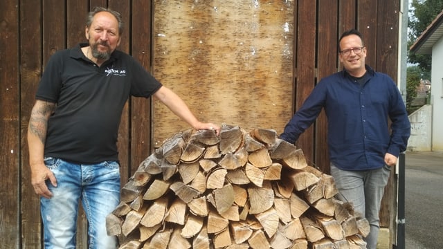 Zwei Männer stehen neben Brennholz Zwei Männer stehen neben Brennholz