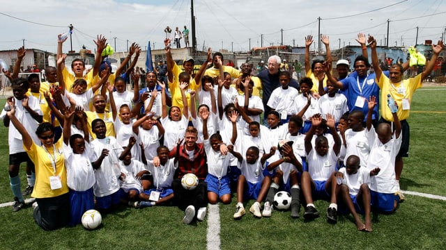 Eine Gruppe Kinder posiert mit David Beckham. Eine Gruppe Kinder posiert mit David Beckham.