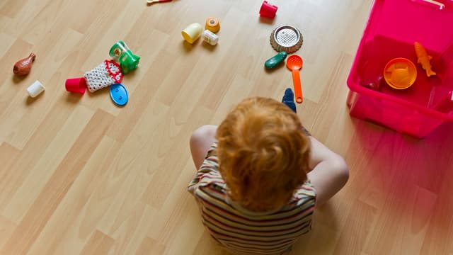 Kind sitzt vor Spielzeug auf dem Boden. Kind sitzt vor Spielzeug auf dem Boden.