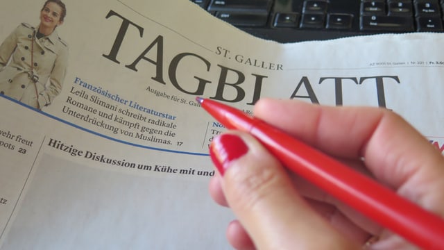 Eine Frauenhand hält einen roten Stift. Eine Frauenhand hält einen roten Stift.