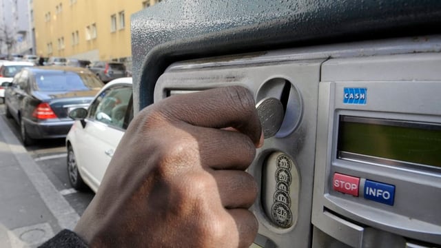 Hand wirft Münze in eine Parkuzr Hand wirft Münze in eine Parkuzr