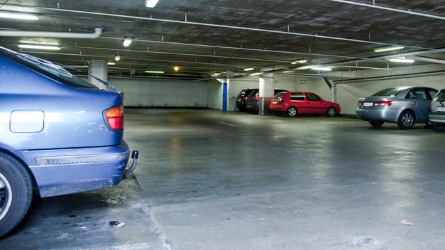 Blick in eine Tiefgarage (Symbolbild): Im Vordergrund ein Auto, hinten mehrere Fahrzeuge und einige leere Parkfelder, Sichtbeton-Bau. Blick in eine Tiefgarage (Symbolbild): Im Vordergrund ein Auto, hinten mehrere Fahrzeuge und einige leere Parkfelder, Sichtbeton-Bau.