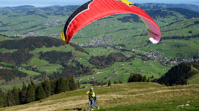 Gleitschirmpilot auf einem Hügel Gleitschirmpilot auf einem Hügel