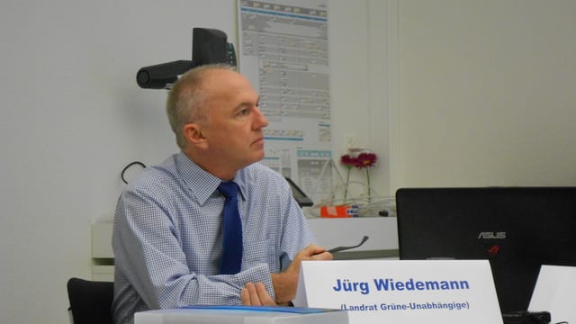 Der Politiker sitzt an einem Tisch und hält seine Brille in der rechten Hand. Der Politiker sitzt an einem Tisch und hält seine Brille in der rechten Hand.
