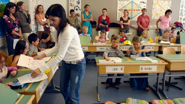Eine Schulklasse mit Lehrerin, im Hintergrund die Mütter der Schüler. Eine Schulklasse mit Lehrerin, im Hintergrund die Mütter der Schüler.
