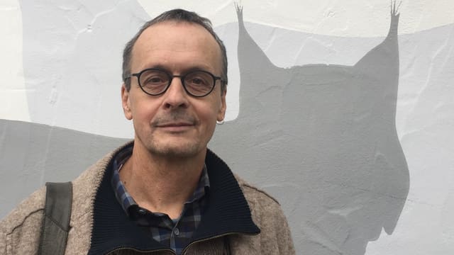 Der Wildtierbiologe Darius Weber vor einem Bild eines Luchses Der Wildtierbiologe Darius Weber vor einem Bild eines Luchses
