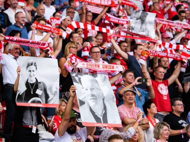 Die Anhänger von Union Berlin halten Bilder verstorbener Klub-Fans hoch.