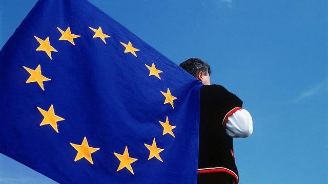 Symbolbild: Ein Fahnenschwinger in Sennentracht hat eine EU-Fahne auf der Schulter. Symbolbild: Ein Fahnenschwinger in Sennentracht hat eine EU-Fahne auf der Schulter.