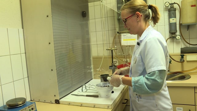 Frau in weissem Kittel steht im Labor und bereitet eine schwarze Salbe zu. Frau in weissem Kittel steht im Labor und bereitet eine schwarze Salbe zu.