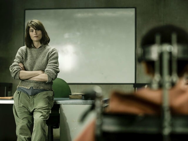 Eine Lehrerin lehnt an ihrem Pult, im Vordergund ein gefesseltes Mädchen. Eine Lehrerin lehnt an ihrem Pult, im Vordergund ein gefesseltes Mädchen.