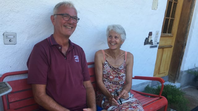 Eine Frau und ein Mann sitzen auf einer Bank vor ihrem Haus. Eine Frau und ein Mann sitzen auf einer Bank vor ihrem Haus.