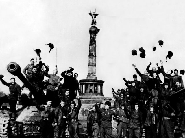 Zwei Panzer stehen vor einem Monument, umringt von vielen, jubelnden Menschen. Zwei Panzer stehen vor einem Monument, umringt von vielen, jubelnden Menschen.
