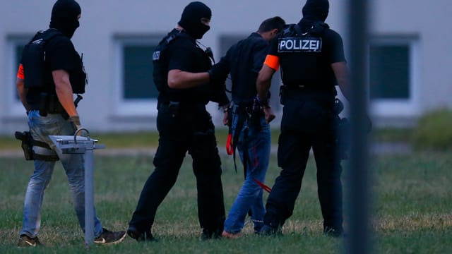 Drei Polizisten und der Tatverdächtige Drei Polizisten und der Tatverdächtige