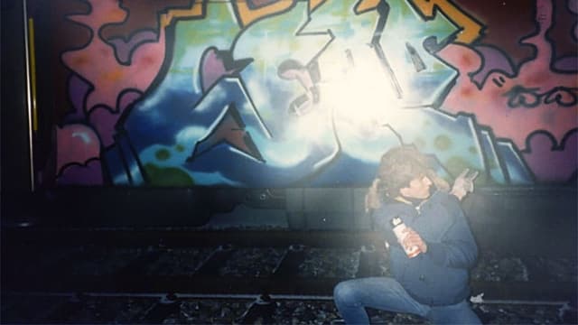Ein Junge steht vor einem mit Graffiti besprayten Zug. Ein Junge steht vor einem mit Graffiti besprayten Zug.