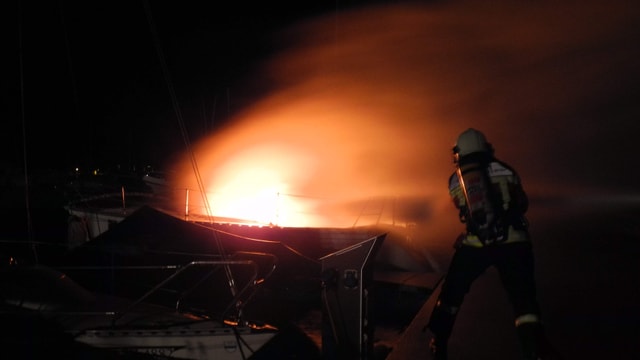 Feuerwehrleute löschen das brennende Segelboot im Bootshafen Aazopf in Arth. Feuerwehrleute löschen das brennende Segelboot im Bootshafen Aazopf in Arth.