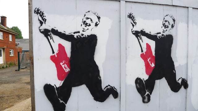 Ein Graffiti-Aufdruck an einer Holzwand in Aldeburgh, der Benjamin Britten mit roter elektrischer Gitarre zeigt. Ein Graffiti-Aufdruck an einer Holzwand in Aldeburgh, der Benjamin Britten mit roter elektrischer Gitarre zeigt.