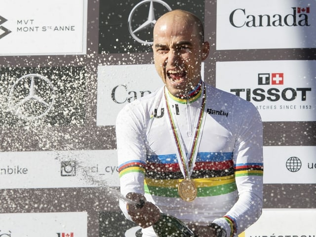 Nino Schurter spritzt aus einer Champagnerflasche. Nino Schurter spritzt aus einer Champagnerflasche.