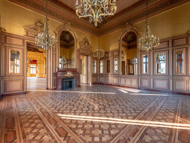 Blick in einen Saal mit aufwendigem Parkett und Kronleuchtern. Blick in einen Saal mit aufwendigem Parkett und Kronleuchtern.