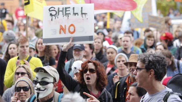 Eine Demonstrantin hält ein Plakat mit der Aufschritt «Shell No» in die Luft Eine Demonstrantin hält ein Plakat mit der Aufschritt «Shell No» in die Luft