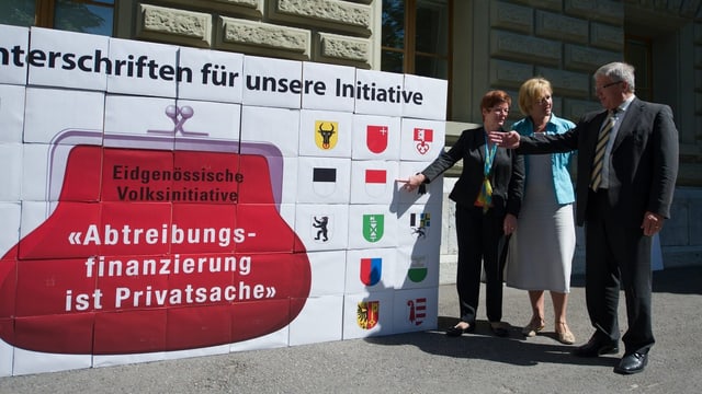 Schachteln mit Unterschriften. Daneben drei Personen. Schachteln mit Unterschriften. Daneben drei Personen.