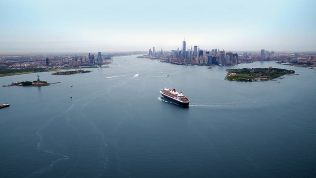 Ein Kreuzfahrtschiff läuft in einer Grosstadt mit vielen Wolkenkratzern ein. Ein Kreuzfahrtschiff läuft in einer Grosstadt mit vielen Wolkenkratzern ein.