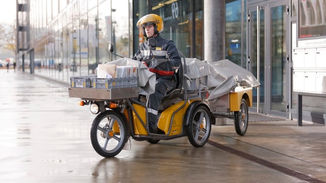 Ein Zustellbote auf einem Dreirad-Elektro-Roller. Ein Zustellbote auf einem Dreirad-Elektro-Roller.