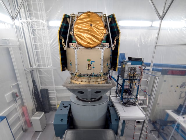 Ein Satellitenmodell mit abgedecktem Teleskop auf einem grossen Tisch. Ein Satellitenmodell mit abgedecktem Teleskop auf einem grossen Tisch.