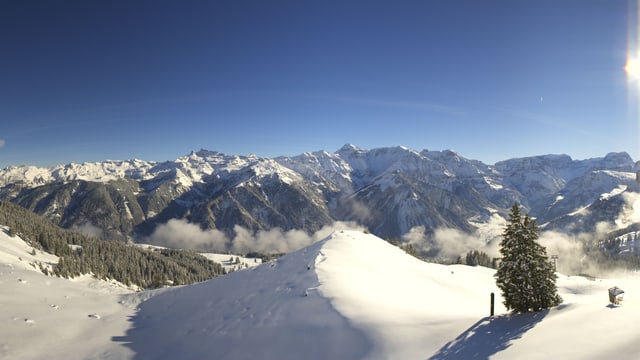 Tief verschneite Berglandschaft unter blauem Himmel Tief verschneite Berglandschaft unter blauem Himmel