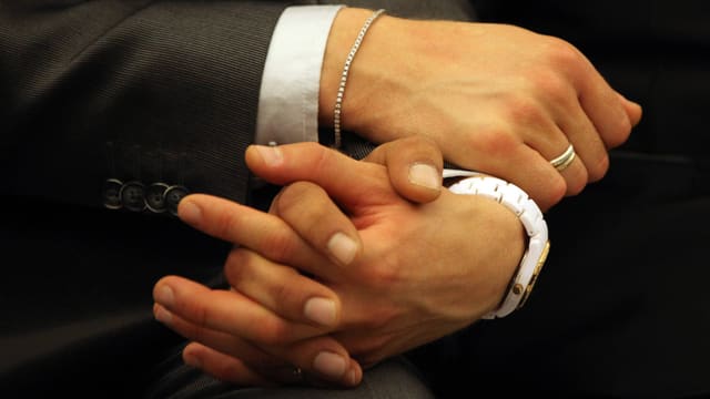 Zwei Männer halten sich die Hand. Zwei Männer halten sich die Hand.