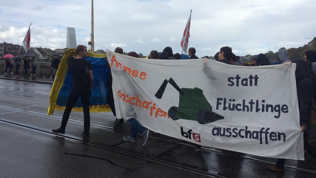 Leute tragen ein Transparent mit der Aufschrift: Armee abschaffen, statt Flüchtlinge ausschaffen. Leute tragen ein Transparent mit der Aufschrift: Armee abschaffen, statt Flüchtlinge ausschaffen.