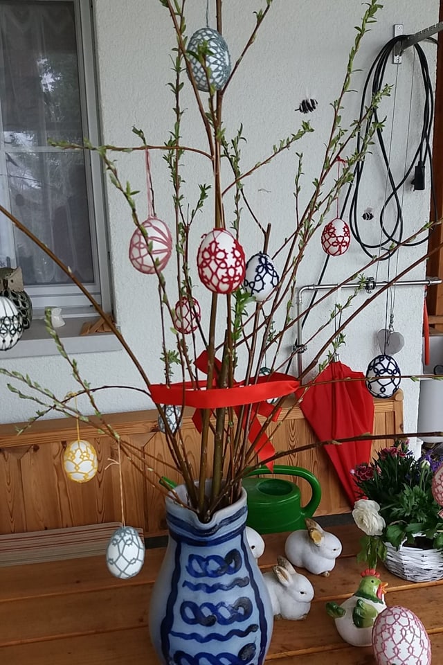 Mit gehäkeltem Schmuck verzierte Ostereier an Zweigen.