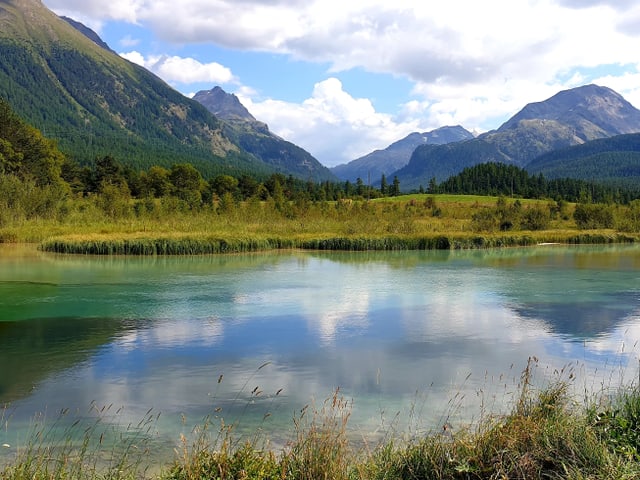 Die Wolken spiegeln sich in der Inn zwischen Celerina und Samedan im Kanton Graubünden.