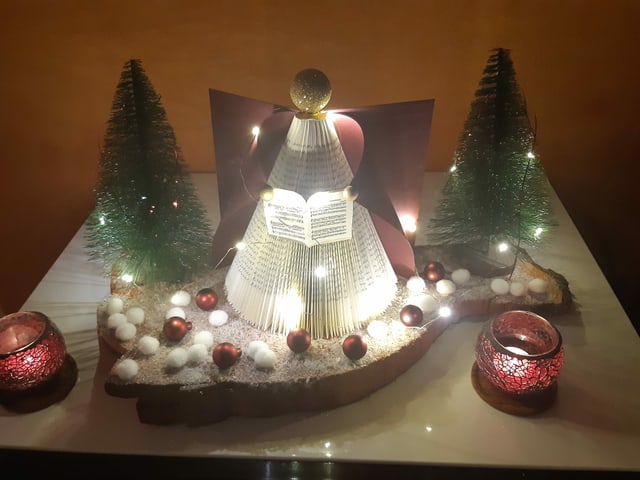 Weihnachtliche Deko mit beleuchtetem Engel, Mini-Tannen und Kerzen.