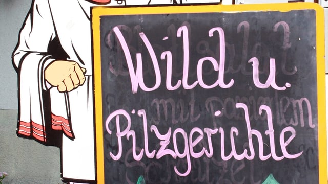 Tafel vor einem Restaurant mit der Aufschrift «Wild u. Pilzgerichte» Tafel vor einem Restaurant mit der Aufschrift «Wild u. Pilzgerichte»