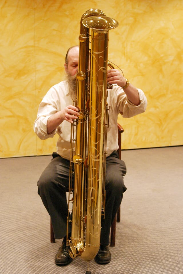Ein Mann spielt auf einem grossen, fast mannshohen Blasinstrument. Ein Mann spielt auf einem grossen, fast mannshohen Blasinstrument.