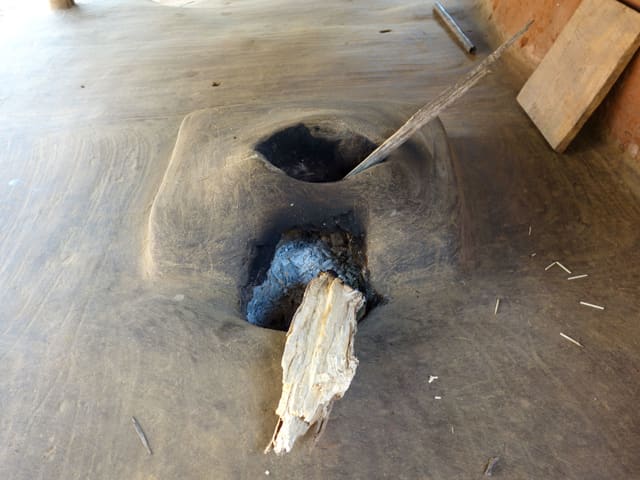 Zwei verrusste Löcher im Lehmboden, in denen Holzscheite stecken. Zwei verrusste Löcher im Lehmboden, in denen Holzscheite stecken.