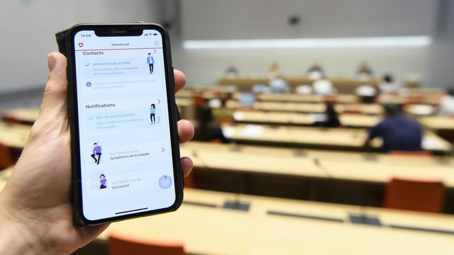 Eine Hand hält die SwissCovid Contact Tracing App auf ihrem Smartphone in die Kamera, fotografiert während einer Medienkonferenz. Eine Hand hält die SwissCovid Contact Tracing App auf ihrem Smartphone in die Kamera, fotografiert während einer Medienkonferenz.