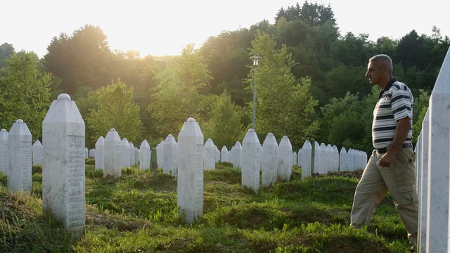 Weisse Grabsteine in mehreren Reihen, von rechts tritt ein Mann ins Bild. Weisse Grabsteine in mehreren Reihen, von rechts tritt ein Mann ins Bild.