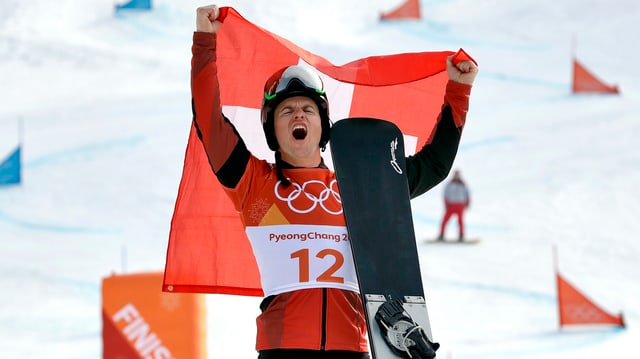 Mann hälft Schweizer Fahne in die Höhe und Snowboard in der Hand Mann hälft Schweizer Fahne in die Höhe und Snowboard in der Hand