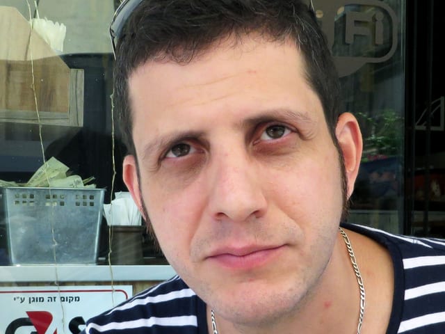 Ein Mann mit gestreiftem T-Shirt und Sonnenbrille im Haar, den Blick gegen oben gerichtet. Ein Mann mit gestreiftem T-Shirt und Sonnenbrille im Haar, den Blick gegen oben gerichtet.