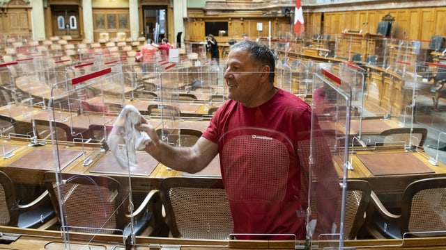 Mann in Arbeitskleidung putzt Plexiglasscheibe mit Tuch. Mann in Arbeitskleidung putzt Plexiglasscheibe mit Tuch.