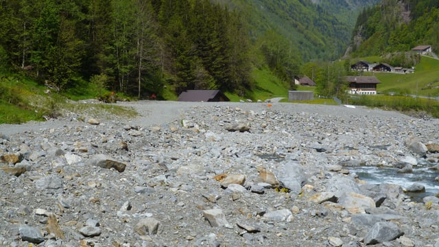 Bachbett mit kleinem Dorf im Hintergrund Bachbett mit kleinem Dorf im Hintergrund