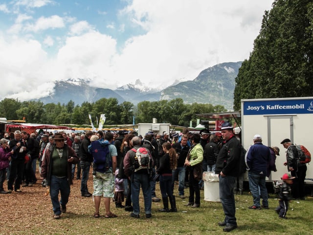 Menschen stehen vor einem Alpenpanorama.