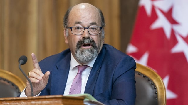 Politiker mit Brille, Veston und Krawatte am Rednerpult im Parlament. Politiker mit Brille, Veston und Krawatte am Rednerpult im Parlament.