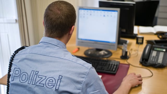 Polizist sitzt vor Computer. Polizist sitzt vor Computer.