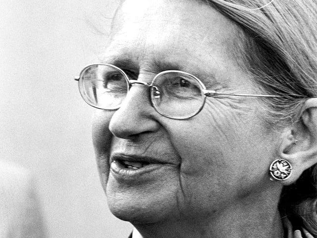 Porträt einer zur Seite blickenden Frau mit zurückgekämmten Haaren und Brille. Porträt einer zur Seite blickenden Frau mit zurückgekämmten Haaren und Brille.