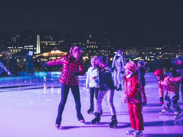 Ex-Weltmeisterin Denise Biellmann erklärt den Kindern auf dem Eisfeld vor der Glasbox, wie eine Pirouette geht.