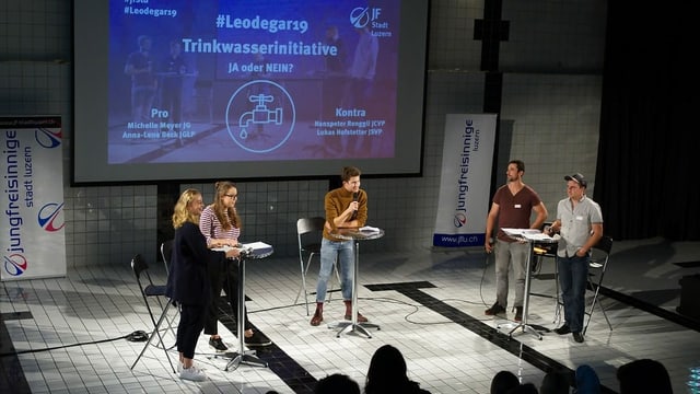 Fünf Leute auf einer Bühne an Stehpulten am diskutieren. Fünf Leute auf einer Bühne an Stehpulten am diskutieren.